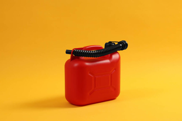 Red plastic canister with tube on orange background - Foto, Imagen