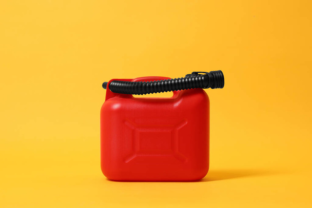 Red plastic canister with tube on orange background - Fotó, kép