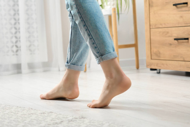 Woman stepping barefoot in room at home, closeup. Floor heating - Fotografie, Obrázek
