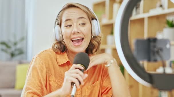 Media, podcast and smile, asian woman with microphone in living room streaming, recording or broadcast from home studio. Video, webinar and vlogging, happy influencer on live stream internet channel - Séquence, vidéo