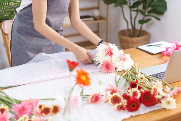 Blumengeschäft Konzept, Floristin Verpackung und Erstellen von bunten Blumenstrauß mit Papier. - Foto, Bild