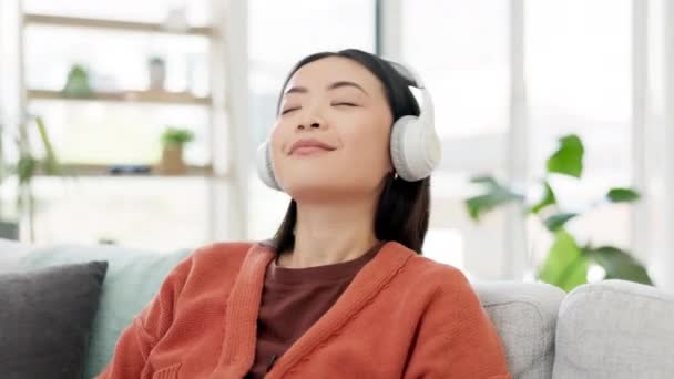 Musiikki, ääni ja nainen rentoutua kuuntelemalla kappaleen kotona istuu sohvalla tai sohvalla nauttia radiosta asunnossa. Iloinen, onnellinen ja nuori olohuoneessa hauskaa kuulokkeet. - Materiaali, video