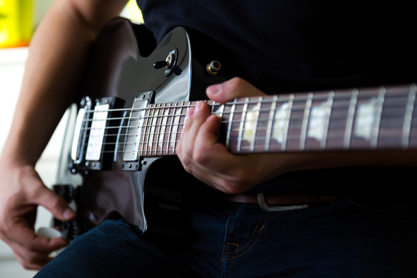 黒のエレク トリック ギターのギタリストのプレイ - 写真・画像