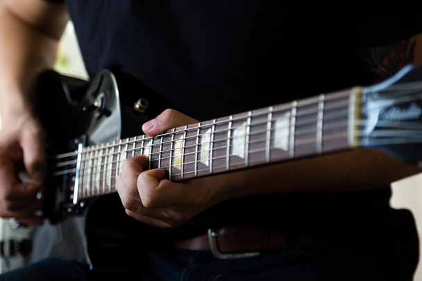 Гитарист играет на чёрной электрогитаре
 - Фото, изображение