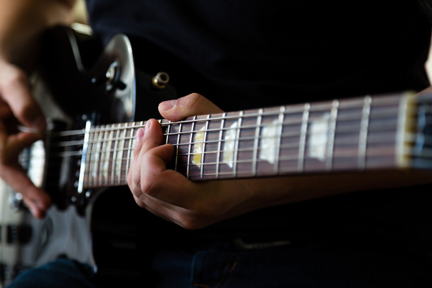 Гитарист играет на чёрной электрогитаре
 - Фото, изображение