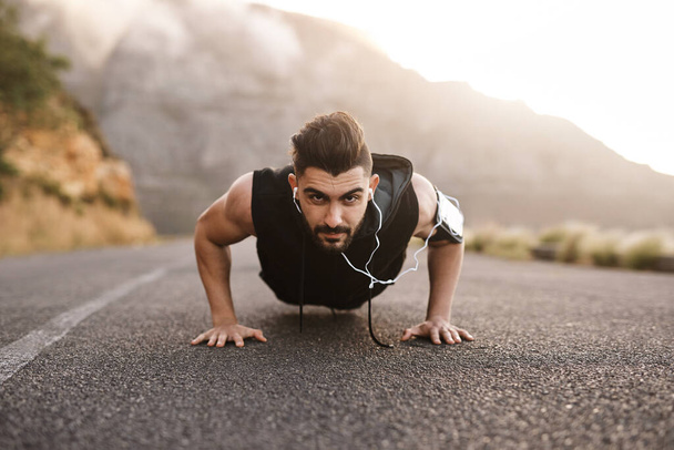 Never underestimate your determination. Portrait of a sporty young man doing pushups while exercising outdoors - Zdjęcie, obraz