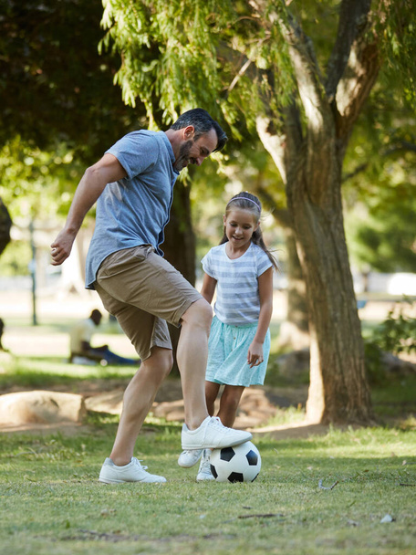 Знаешь, раньше папа был футболистом. прелестная маленькая девочка играет в футбол со своим отцом в парке - Фото, изображение