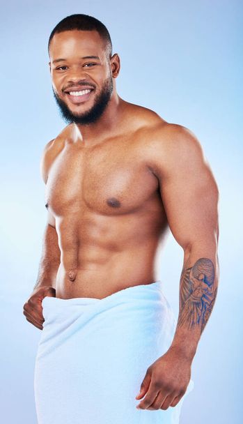 Black man, bodybuilder and towel in studio portrait with smile, wellness or start to morning by blue background. Youth african guy, body and skincare with happiness, health and self care by backdrop. - Photo, Image