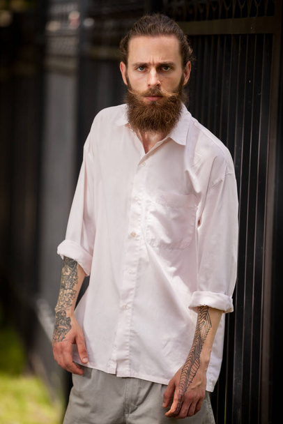 Cool uitziende hipster man met lange baard poseren buiten in de stad. Stijl en diversiteit - Foto, afbeelding