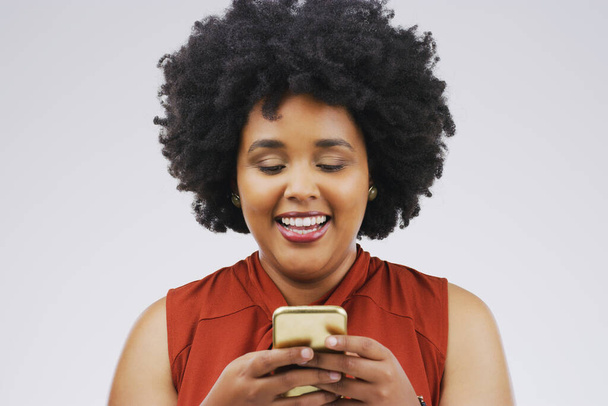 Wyślij komuś specjalnemu SMS-a i spraw, żeby się uśmiechnął. Studio zdjęcia młodej kobiety korzystającej z telefonu komórkowego na szarym tle - Zdjęcie, obraz