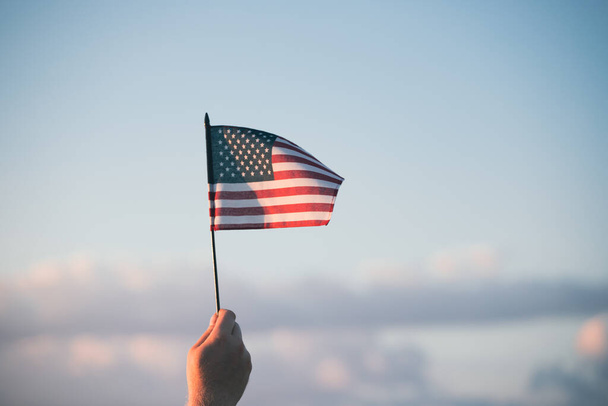 Man holding american USA flag in the sunset. Independence Day or traveling in America concept. - Foto, imagen