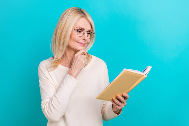Photo of old lady minded reading planner blonde hair touch chin important information about finance economy isolated on aquamarine color background. - Foto, afbeelding