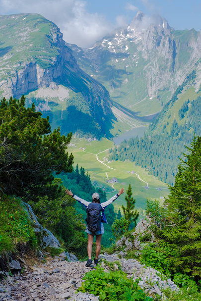 Asian women with hands up hiking in the Swiss Alps mountains during summer vacation with a backpack and hiking boots. woman walking on the Saxer Lucke path - Photo, Image