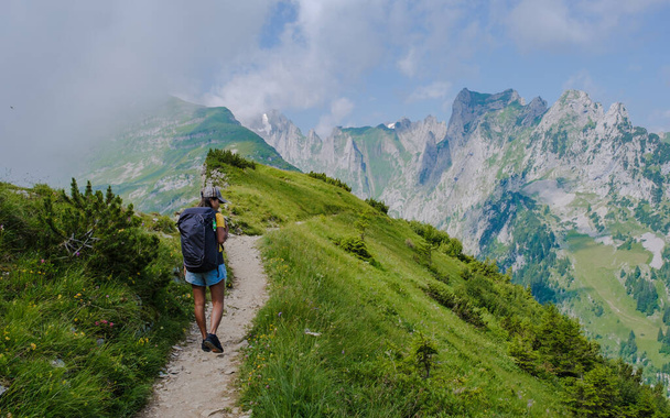 Yaz tatilinde sırt çantası ve yürüyüş botlarıyla İsviçre Alp Dağları 'nda yürüyüş yapan Asyalı kadınlar. Sakson şansı yolunda yürüyen bir kadın. - Fotoğraf, Görsel