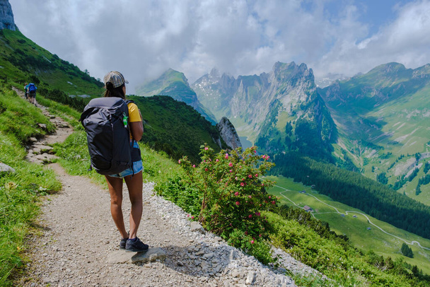 vrouwen wandelen in de Zwitserse Alpen tijdens de zomervakantie met een rugzak en wandelschoenen. vrouw wandelen op de Saxer Lucke pad - Foto, afbeelding
