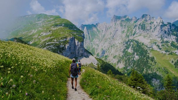 Asian women hiking in the Swiss Alps mountains during summer vacation with a backpack and hiking boots. woman walking on the Saxer Lucke path a popular hiking trail in Switzerland - Photo, Image