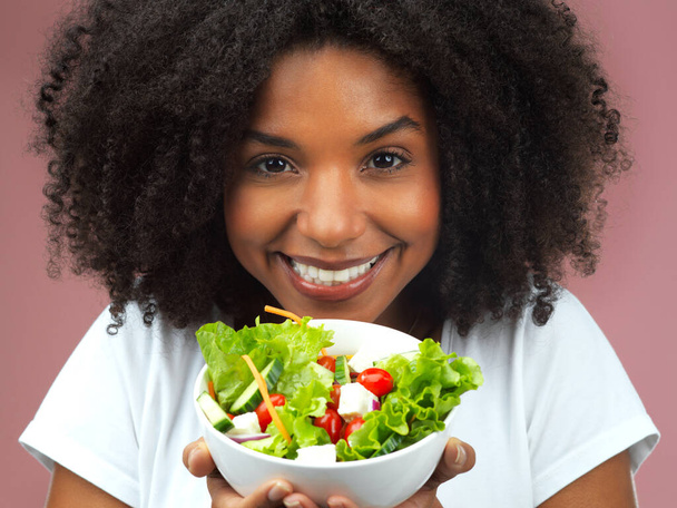 Eres lo que comes. Captura de estudio de una atractiva joven mujer comiendo ensalada sobre un fondo rosa - Foto, imagen