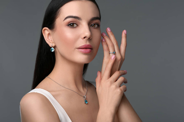 Beautiful young woman with elegant jewelry on dark grey background - Foto, immagini
