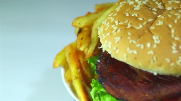 Hamburger mit Bratkartoffeln in Rotation auf weißem Hintergrund. Makro - Filmmaterial, Video