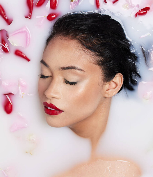 Rose milk bath, natural beauty and red lipstick of an Asian woman with makeup and cosmetics. Above, skincare and wellness of a female model with dermatology, flower aromatherapy and spa treatment. - 写真・画像