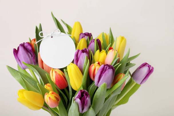 Bouquet of colorful tulips with blank card on white background, closeup - Foto, imagen