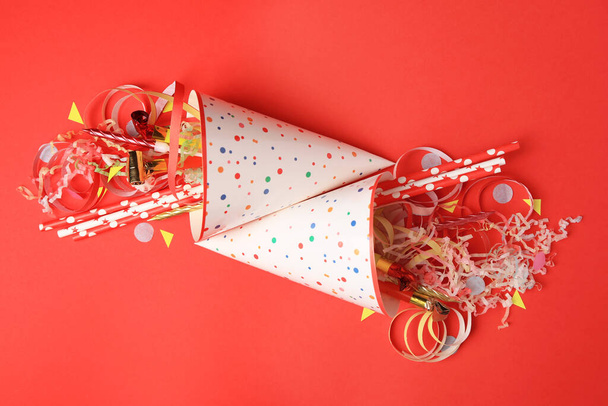 Party hats and different festive items on red background, flat lay - Photo, image