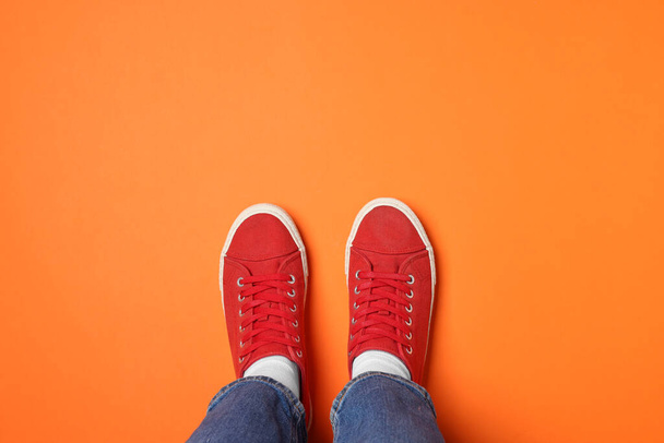 Woman in stylish sneakers on orange background, top view. Space for text - Foto, immagini