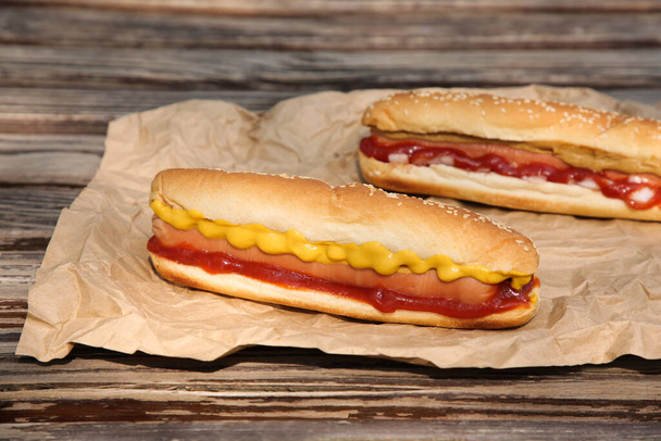 Fresh delicious hot dogs and sauces on wooden surface - Foto, Imagem