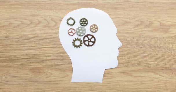 Papírová silueta muže s kovovými ozubenými koly v mozku detailní 4k filmu. Pojem znalostí a talentu - Záběry, video