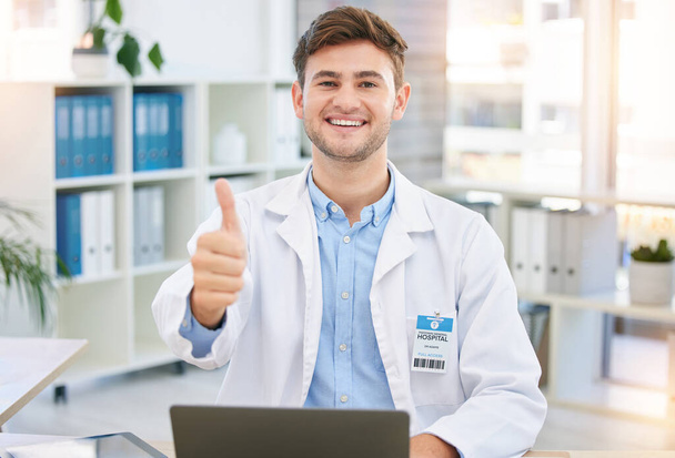 Thumbs up, doctor and portrait of man in hospital office with laptop for wellness, telehealth and medical research. Healthcare, hand emoji and happy health worker for consulting, yes sign and support. - Фото, зображення