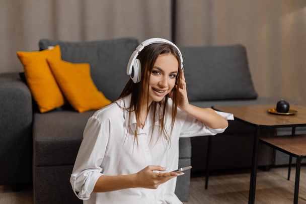 Teen  student girl wear headphones  using smartphone and watching online video course at home - Photo, image