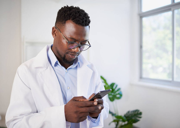 Detailní záběr černého doktora, jak píše na mobil v moderní klinice. Kvalitní fotografie - Fotografie, Obrázek