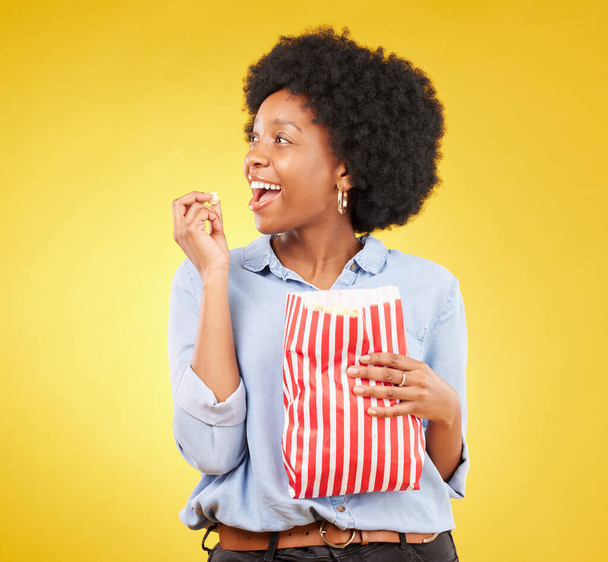 Happy, eating and popcorn with black woman in studio for movie, streaming service and cinema. Television, smile and theatre with female and snack isolated on yellow background for food, tv and film. - Foto, Bild