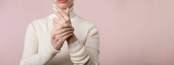 Asijské mladá žena s bílým svetrem látka trpí zápěstím bolest rukou zranění. Příčiny poranění zahrnují syndrom karpálního tunelu, zlomeniny, artritidu nebo prst spouště. Koncept zdravotní péče. - Fotografie, Obrázek