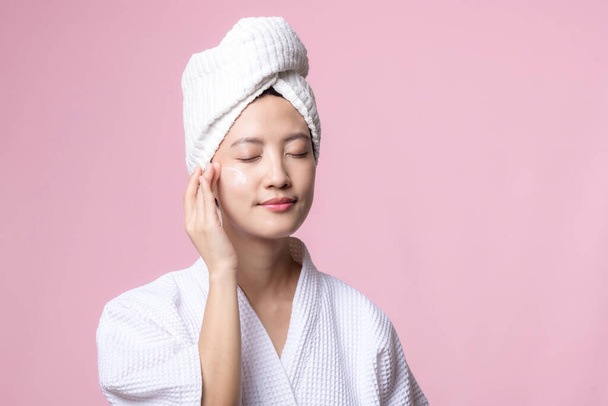 Young beautiful asian woman happy with clean face skin in towel and bathrobe, spa suit on pink background. Skincare, treatment, wellness therapy, facial care, beauty female health, cosmetology concept - Fotoğraf, Görsel
