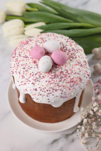 Tasty Easter cake with decorative sugar eggs and flowers on white marble table, above view - Foto, afbeelding