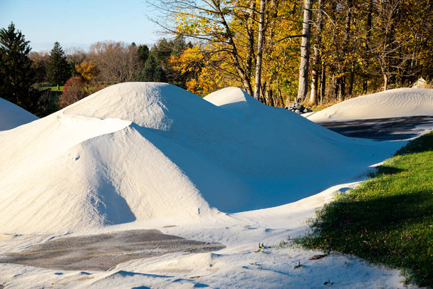 Primer plano gran pila de arena blanca fina pila para llenar y mezclar en proyecto de remodelación de campos de golf en Rochester, Nueva York, EE.UU.. Sitio de construcción con montículo de hojas de otoño de arenas grises y blancas - Foto, imagen