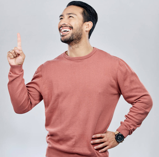 Happy, smile and pointing with man in studio for idea, product placement and announcement. Success, confident and direction with male isolated on white background for positive, advertisement or pride. - Foto, Imagem