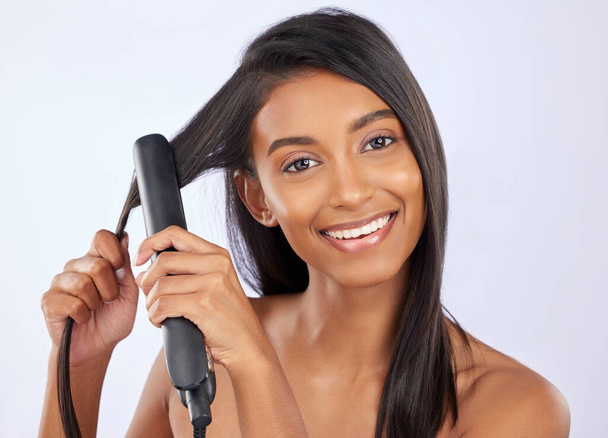 Beauty, health and woman with hair straightener in studio for a straight, long and healthy hairstyle. Happy, smile and portrait of female model with flat iron after hair treatment by gray background - Photo, image