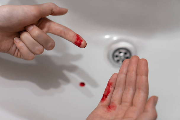 Primo piano del dito tagliato di una donna nel sangue sopra il lavandino - Foto, immagini