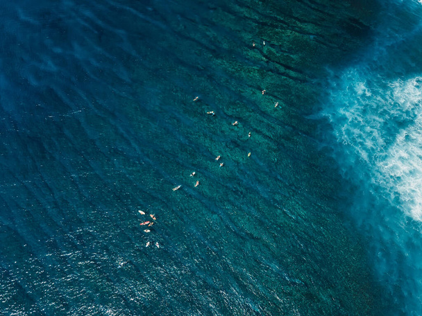 Surferzy w przezroczystym błękitnym oceanie. Miejsce do surfowania na tropikalnej wyspie. Widok z lotu ptaka. - Zdjęcie, obraz