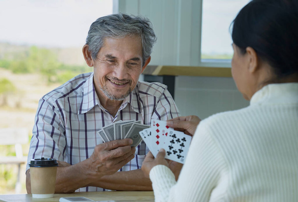 happy senior couple enjoy playing cards game together, concept elderly pensioner lifestyle, entertainment, recreation, encourages social interaction, help memory retention  - Фото, изображение