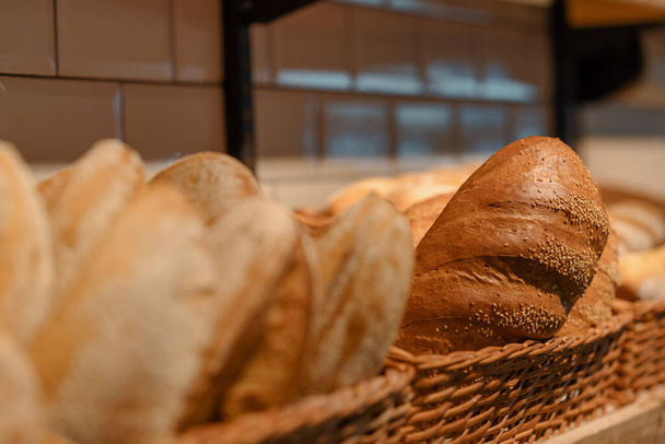 Freshly baked bread is served in baskets on the bakery counter close-up view - Фото, изображение