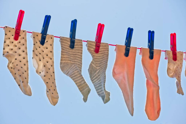 Děti ponožky sušení vzduchu visí na prádelní šňůře v jasný den s modrou oblohou. - Fotografie, Obrázek