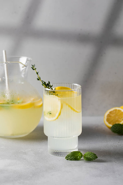 Homemade lemonade with fresh lemon slices and mint leaves in a glass. A summer refreshing drink with lemon. - Fotoğraf, Görsel
