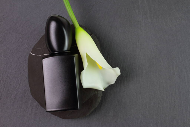 Black glass perfume bottle and white lily flower, mockup - Φωτογραφία, εικόνα
