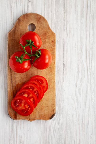 Raw Red Organic Tomaten op een rustiek houten bord, bovenaanzicht. Platte vloer, boven, van boven. - Foto, afbeelding