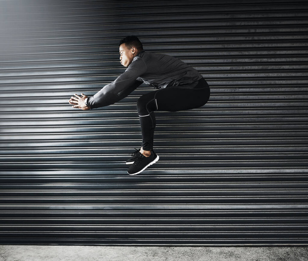 Be courageous enough to jump over any hurdle. a sporty young man jumping against a grey background - Photo, Image