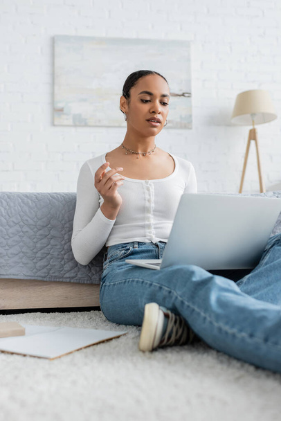 pretty african american woman in jeans watching webinar on laptop  - Photo, Image