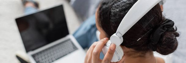 top view of african american student wearing wireless headphones while listening audio book and using laptop, banner  - Photo, Image